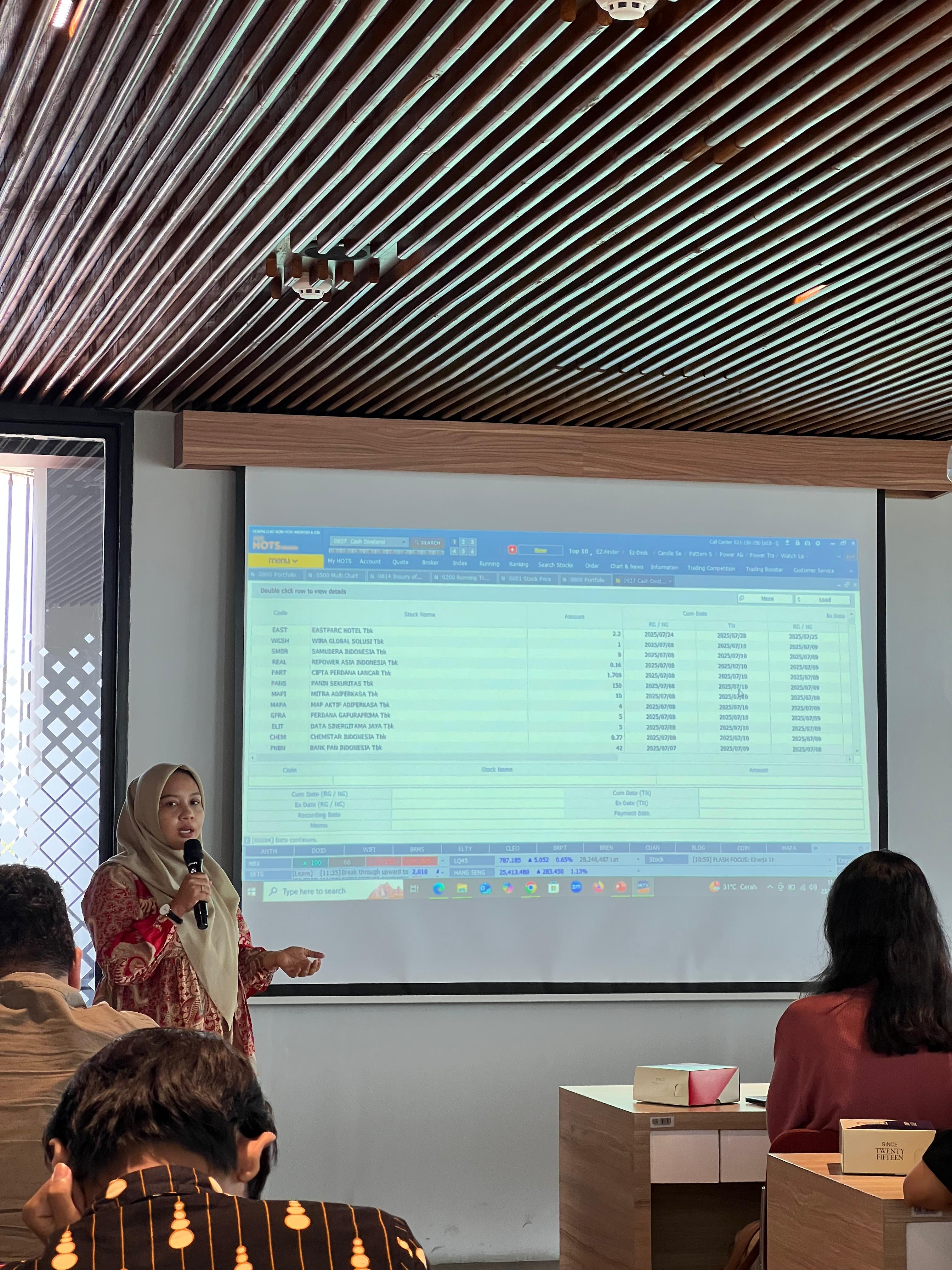 Pembicara memaparkan analisis saham di ruang meeting modern
